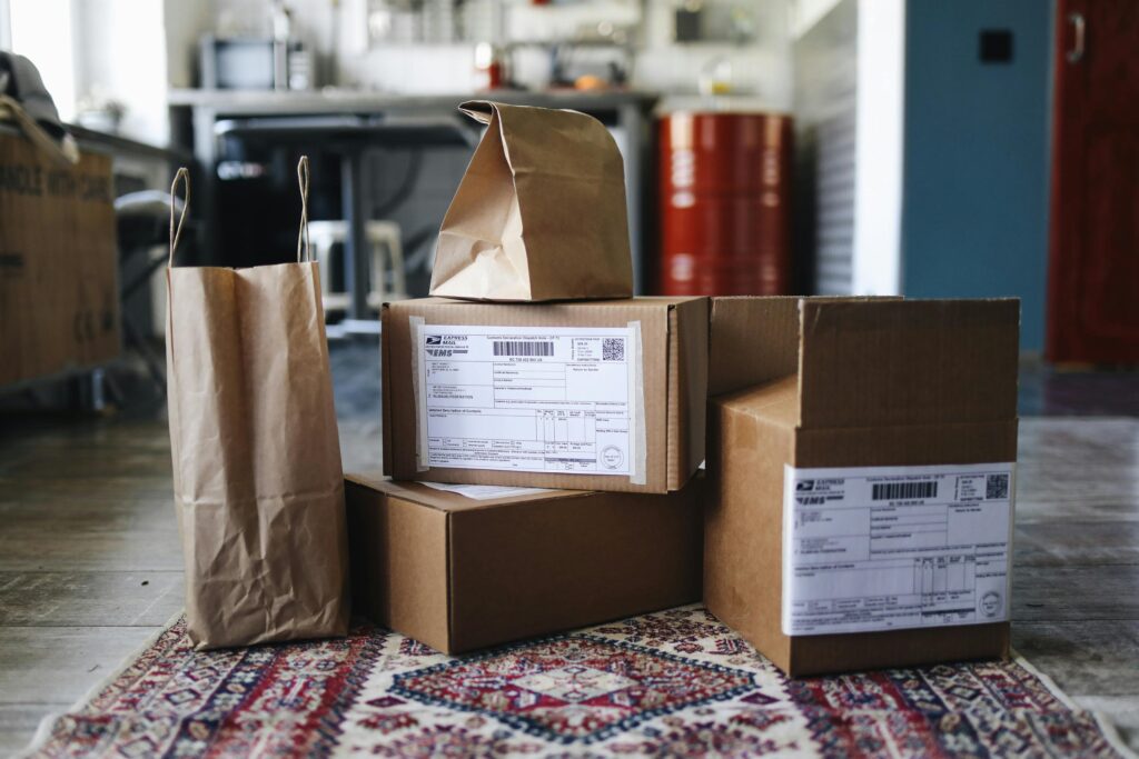 pexels-photo-4440841-4440841 A collection of cardboard boxes and paper bags on a patterned rug in a home setting.